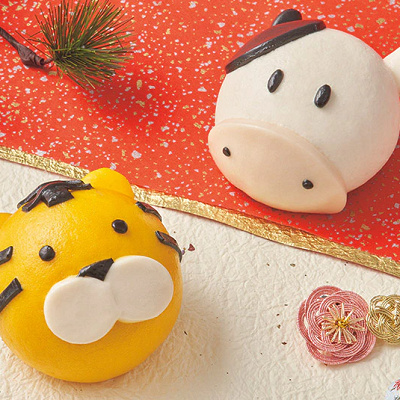 ゆく年まん ～モウモウチーズケーキ～（右）とくる年まん ～坦々タイガー～（左）
